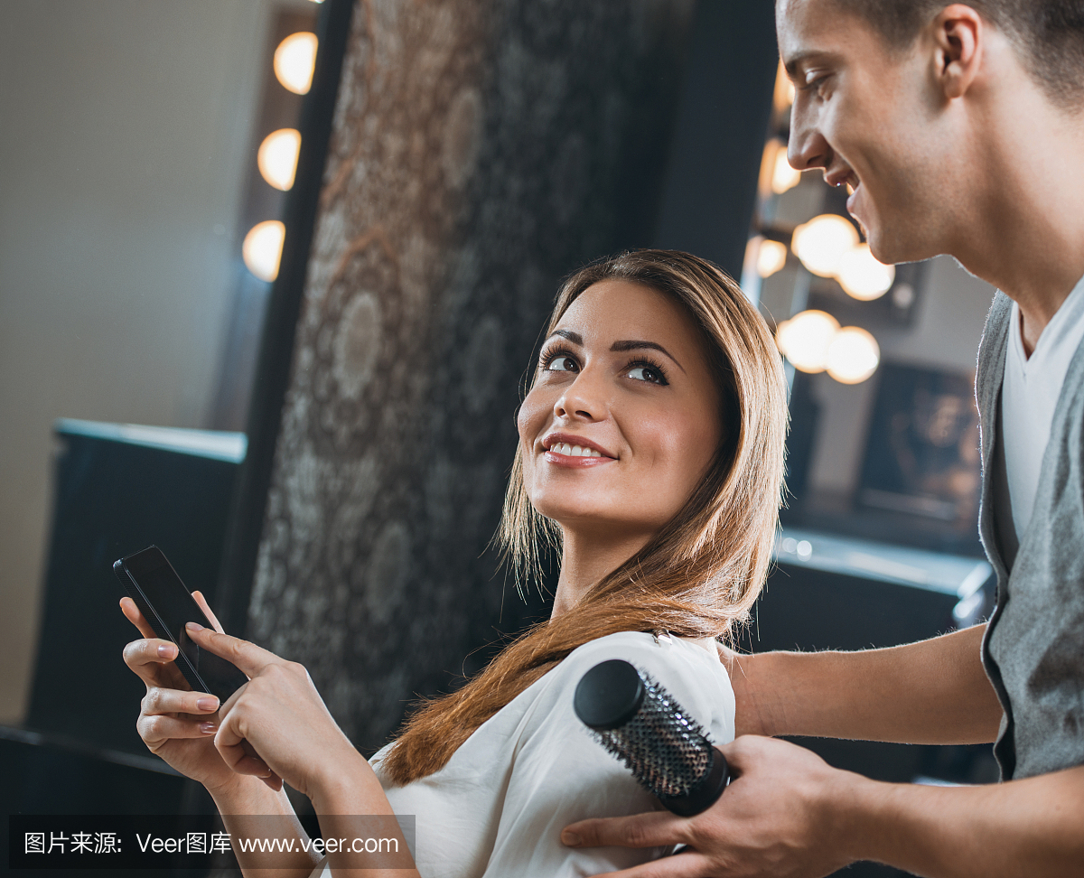 微笑的女人在手机上显示她的美发师短信