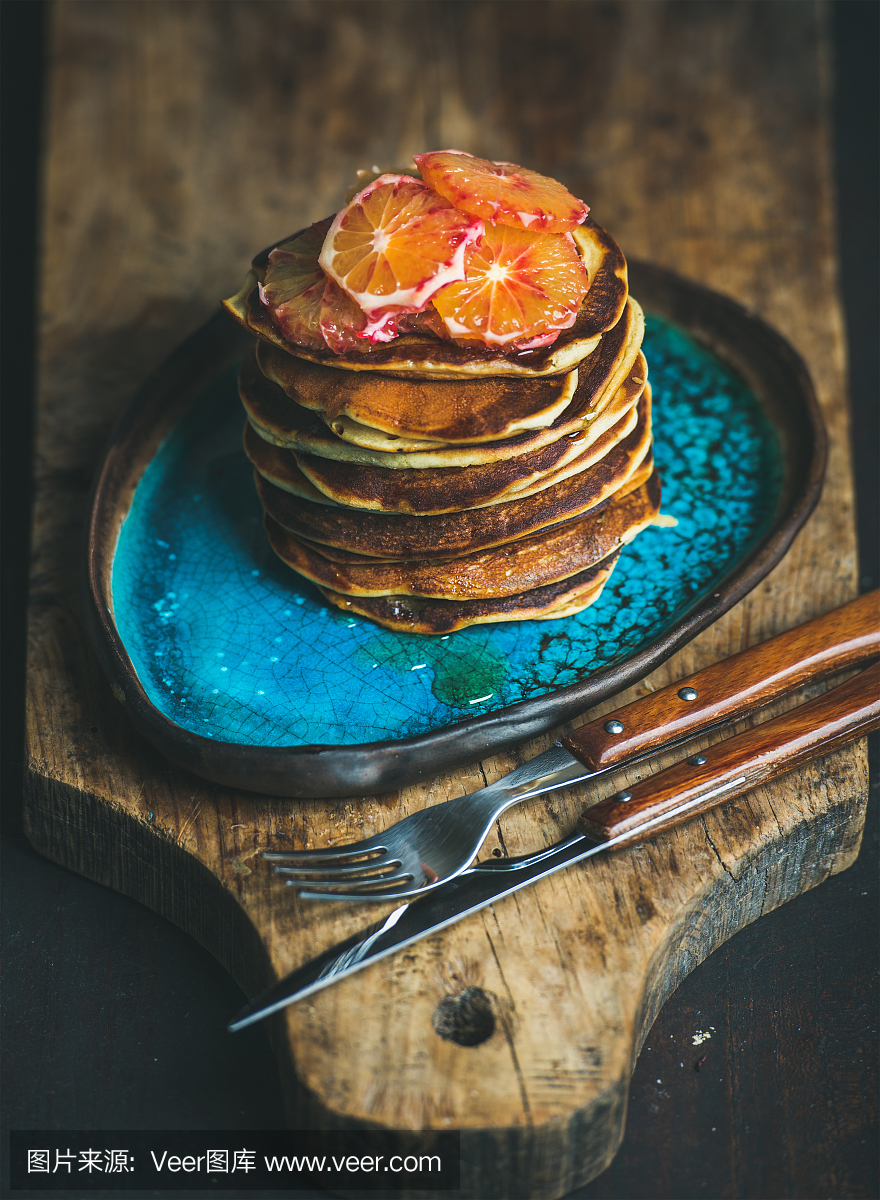 在蓝色的盘子上用蜂蜜和血色橙色切片煎饼