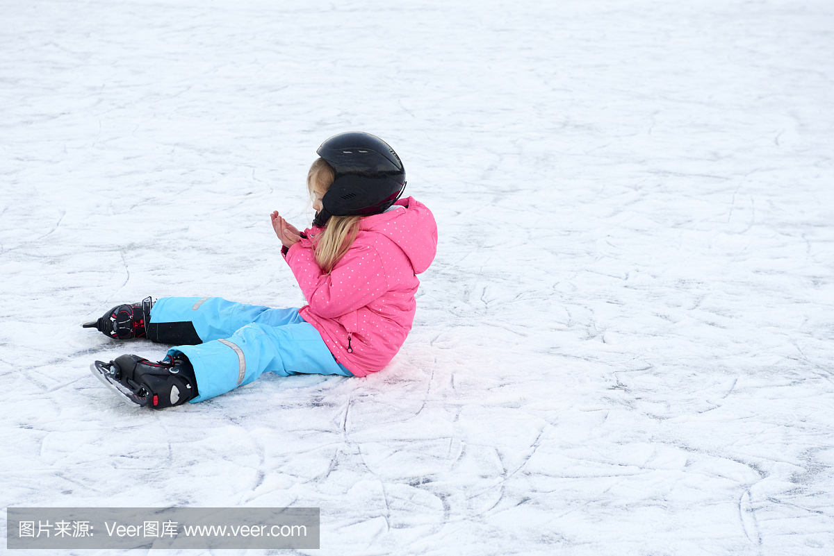 落下后坐在冰上的小女孩。戴安全帽