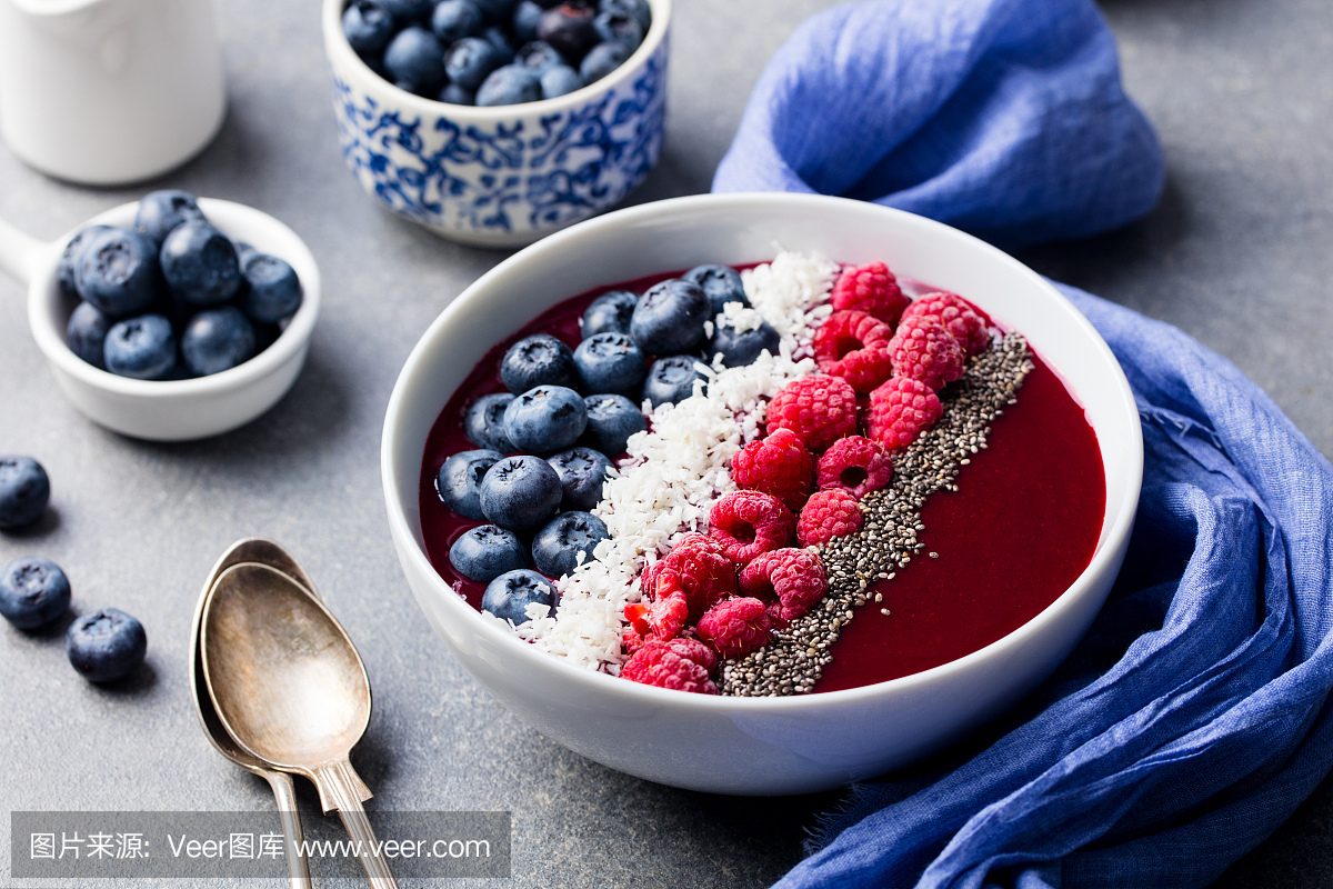 思慕雪碗与新鲜树莓,蓝莓,椰子片和奇亚籽。灰
