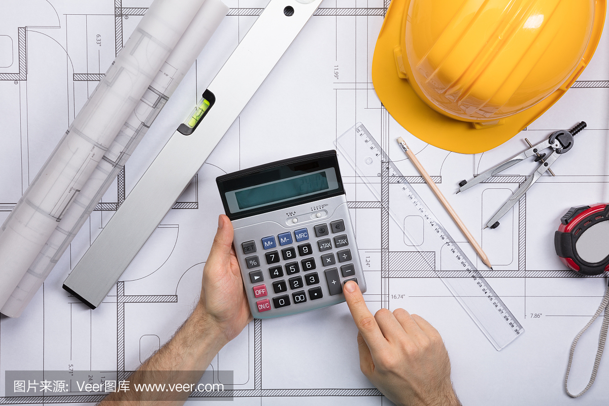 建筑师使用计算器工作在蓝图上的手
