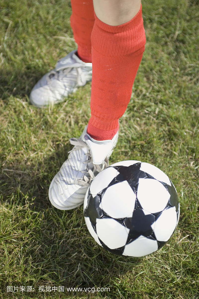 足球运动员的脚旁边一个足球与星形状在草地上