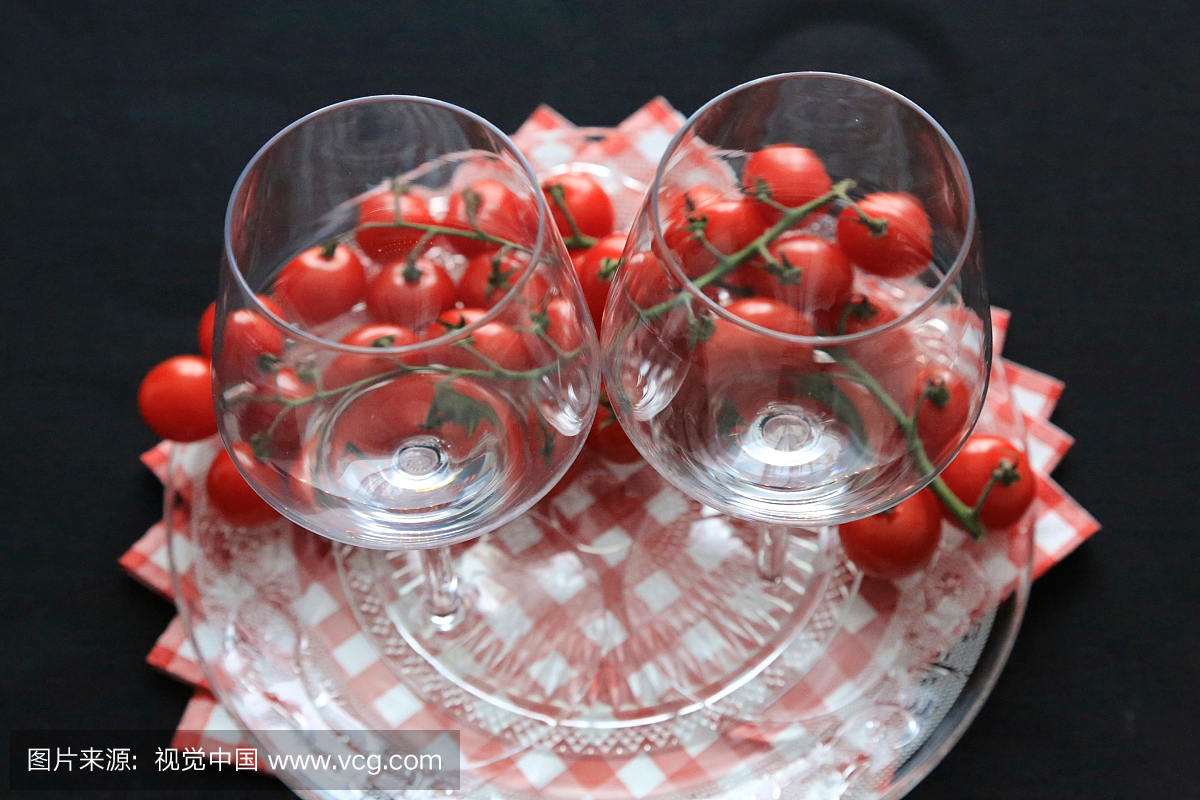新鲜的红色樱桃和葡萄酒杯在黑色背景上的特写