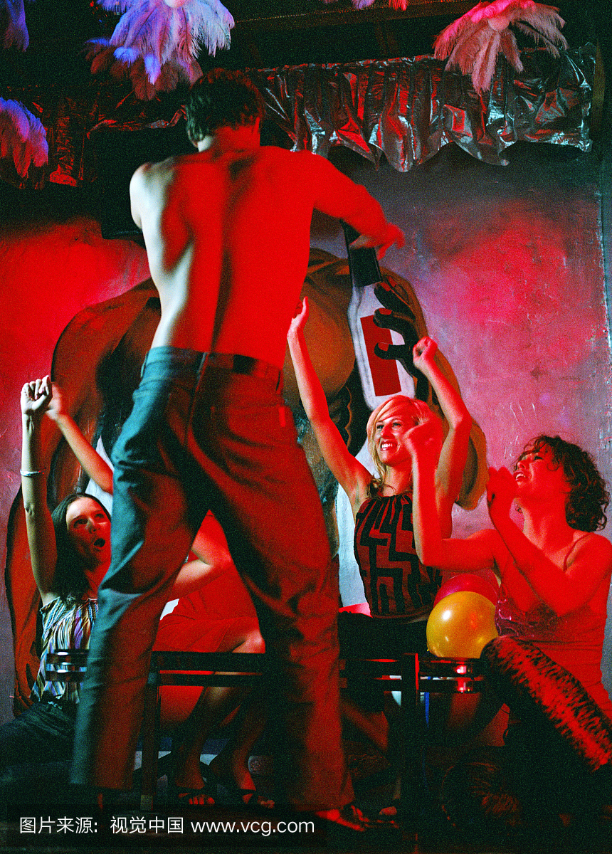 在一群年轻女子面前的一个年轻人跳舞的后视图