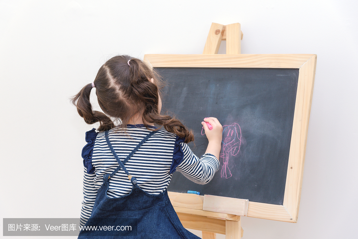 快乐的亚裔女孩孩子绘画卡通与粉笔在黑板上学