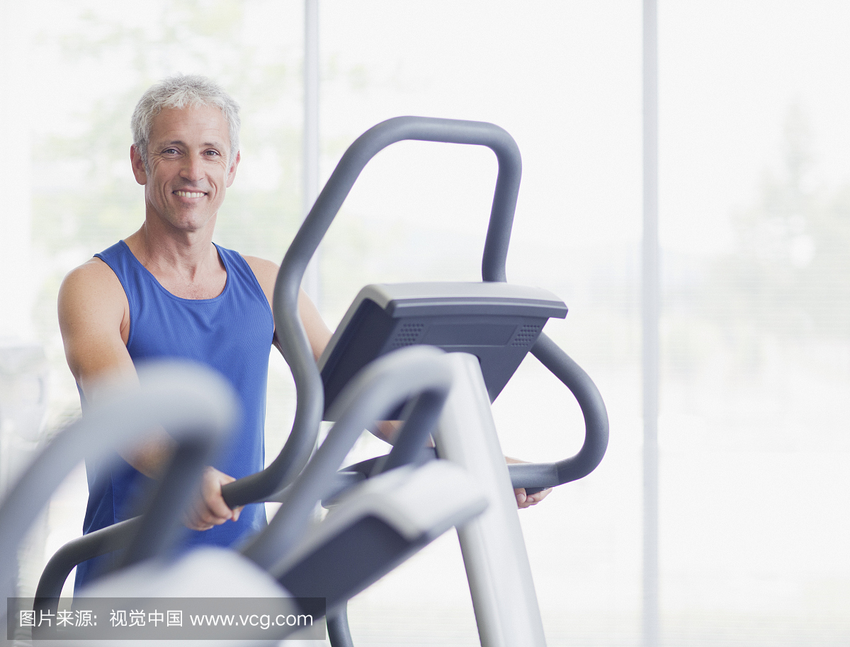 在健身房的椭圆机上的微笑的人的肖像