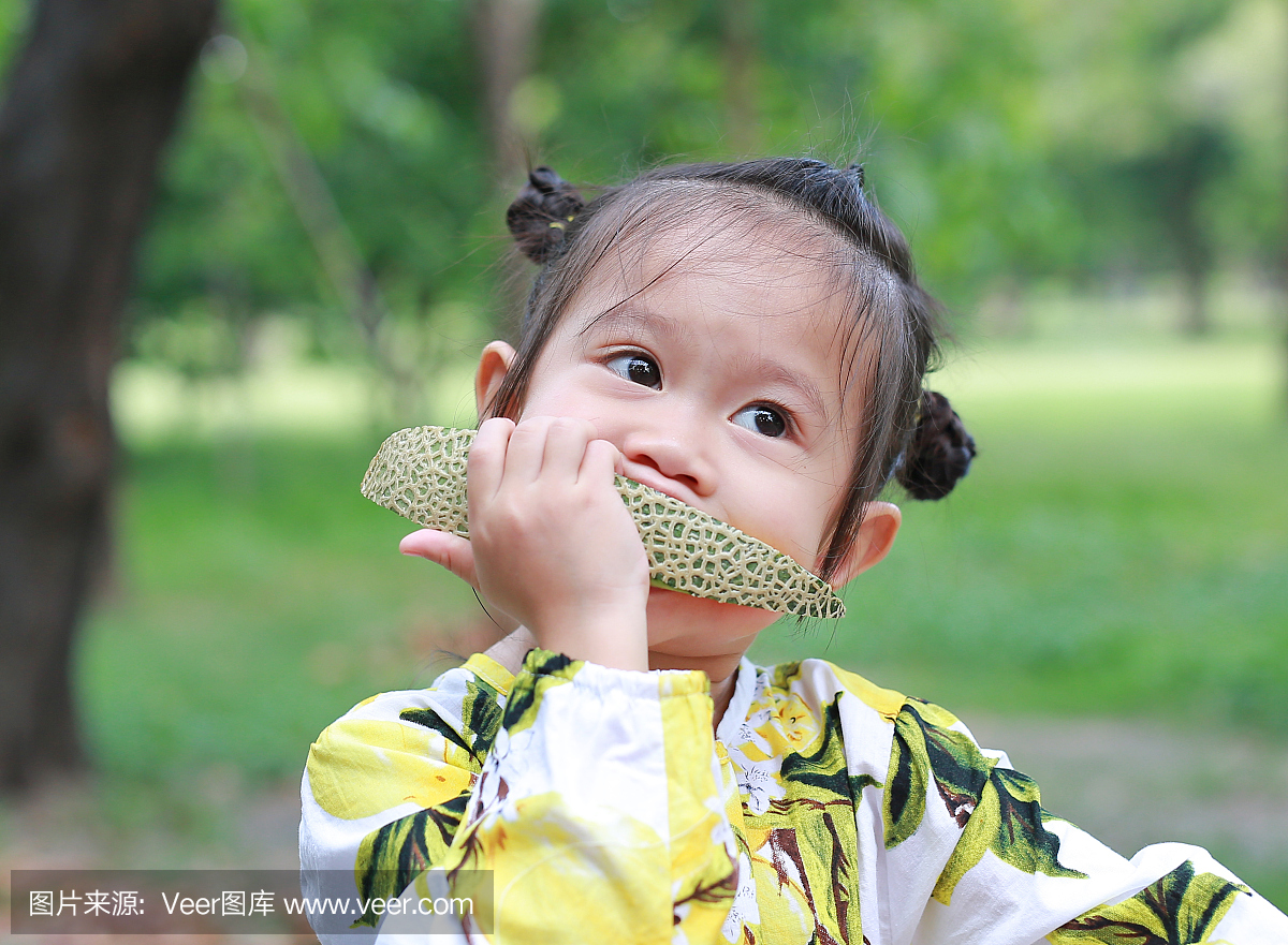 儿童女孩在公园里吃切片哈密瓜甜瓜。