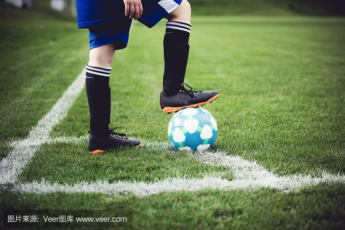 踢足球的孩子在当地体育场外面在草地上。较低