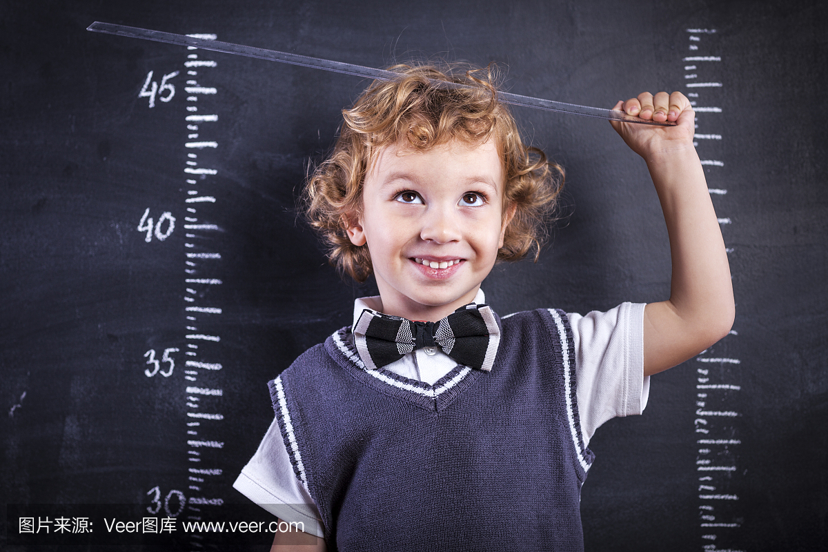 可爱的小男孩用尺子测量身高