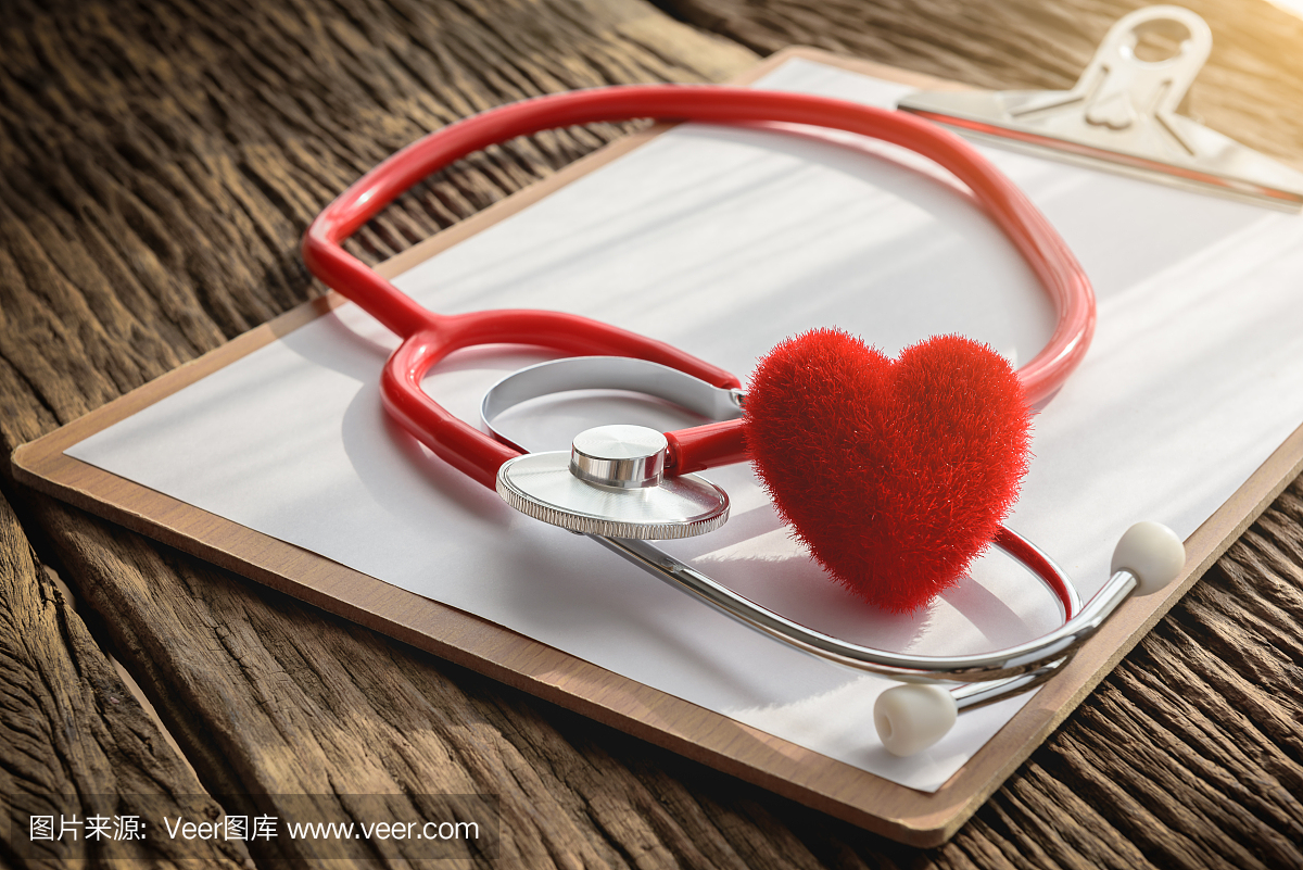 医生工作区用听诊器,剪贴板和心脏在木桌上