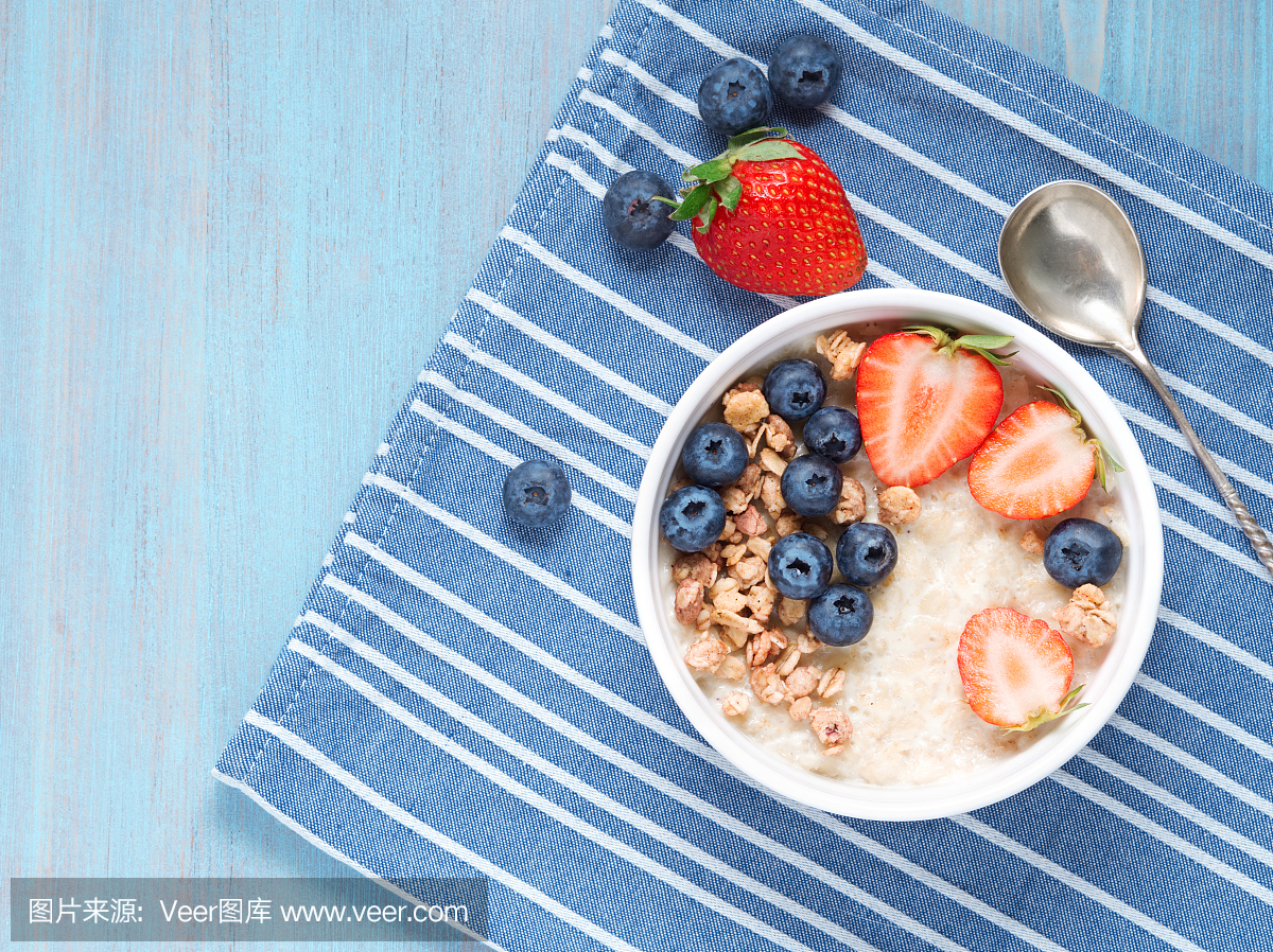 新鲜的草莓,蓝莓燕麦粥,对比蓝色背景格兰诺拉