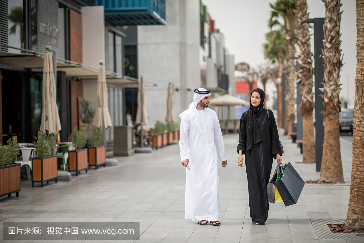 中东购物夫妇穿着传统服装,携带购物袋,迪拜,阿