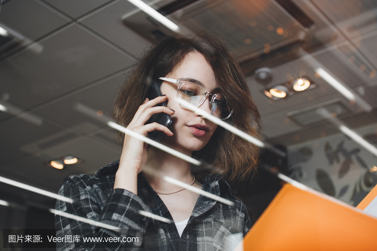 女子谈电话与发展在晚上办公室和拿着文件夹文