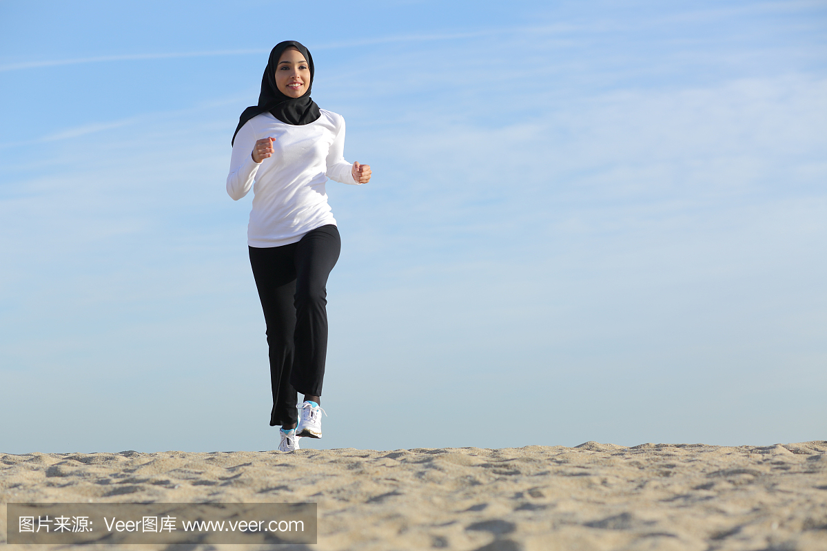在沙滩上运行的阿拉伯沙特阿拉伯酋长国的女人