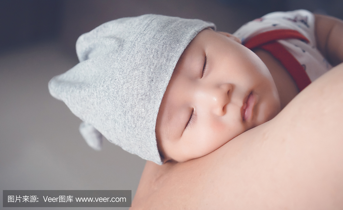 疲倦的婴儿戴着帽子睡在父亲的怀里