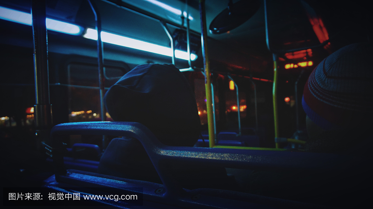 在晚上坐公共汽车的人的后视图