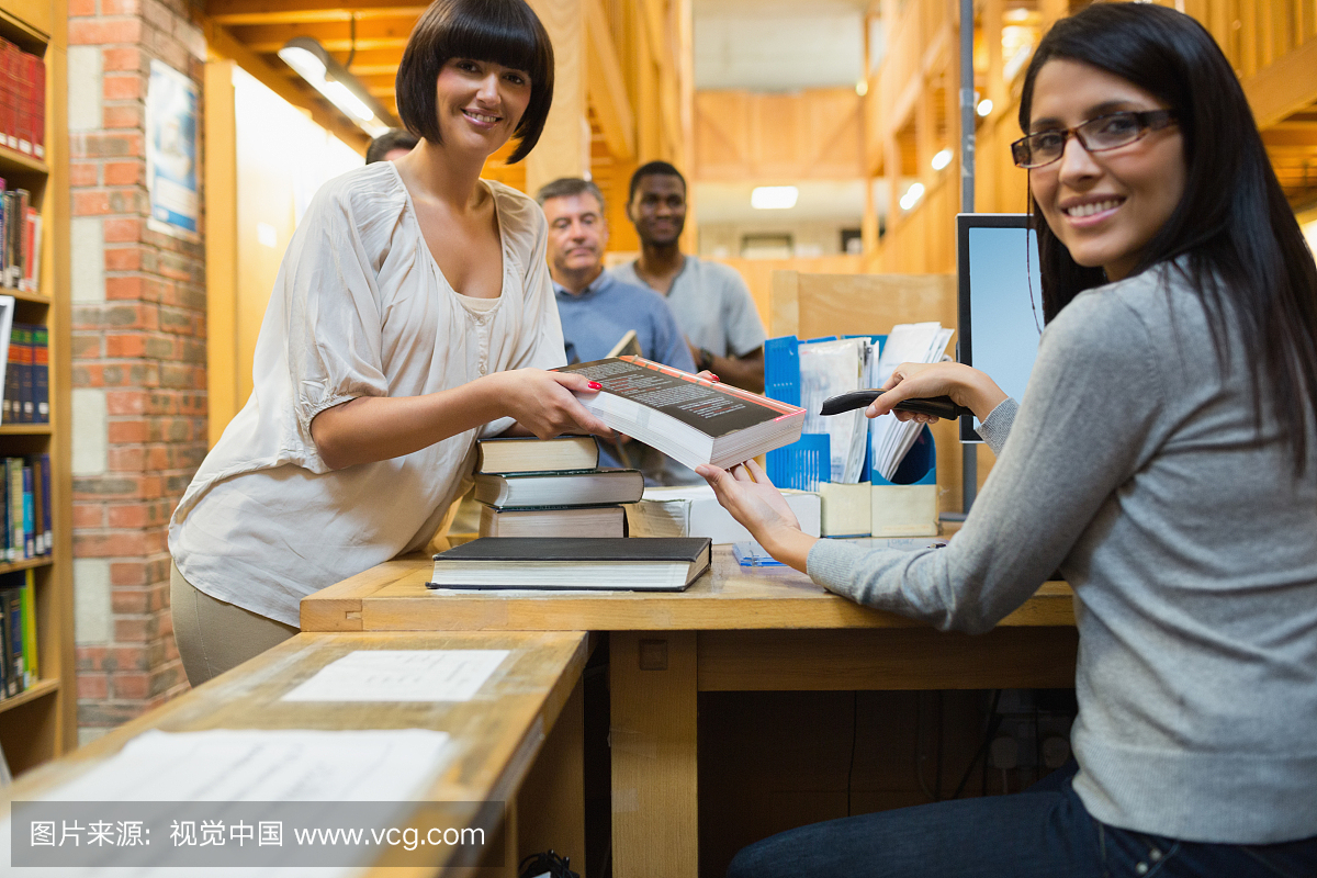 Librarian scanning book and handing to woman