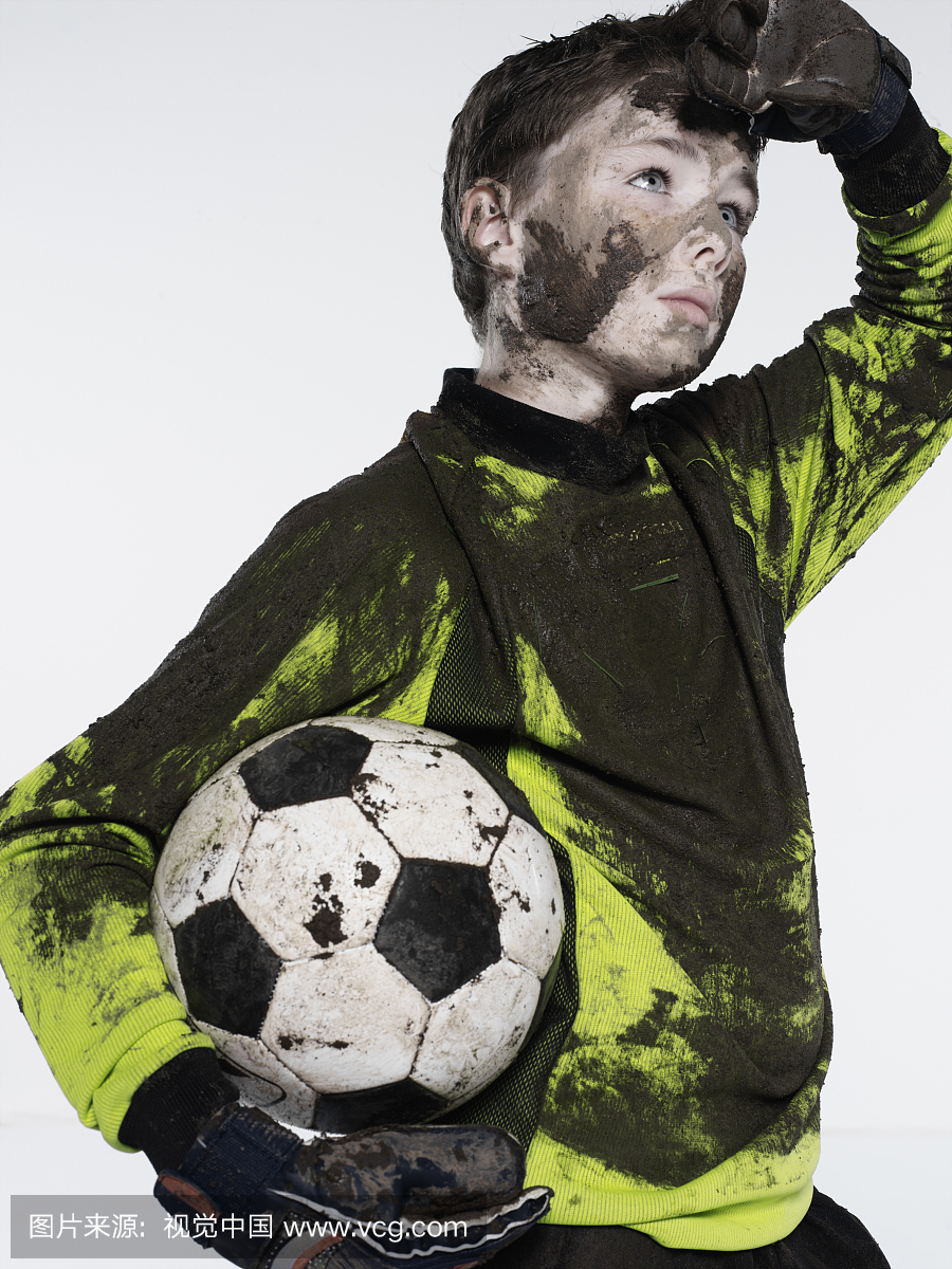 男孩(11-13)足球守门员覆盖着泥土,摩擦额头