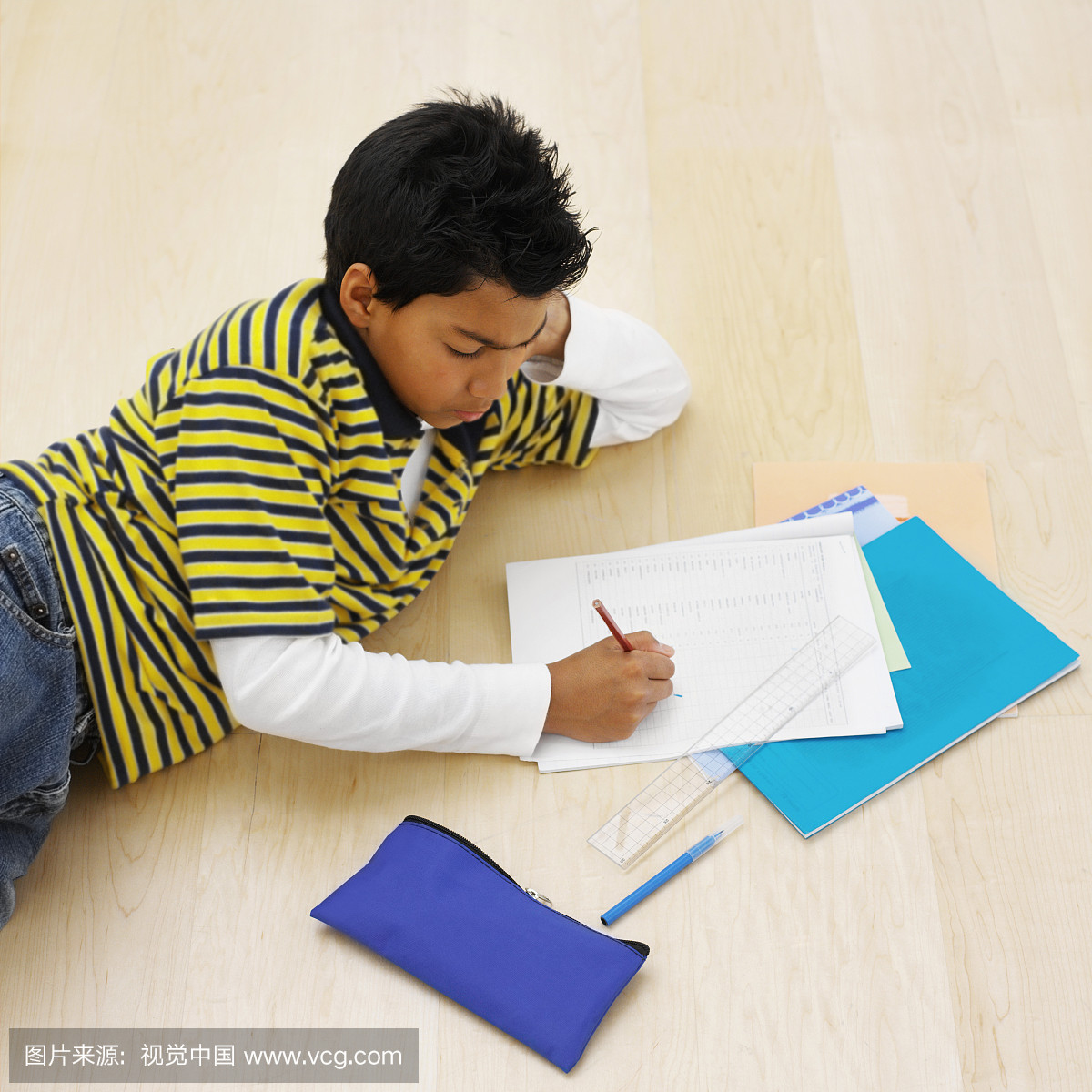 一个男孩写在纸上,躺在地上的高角度视图