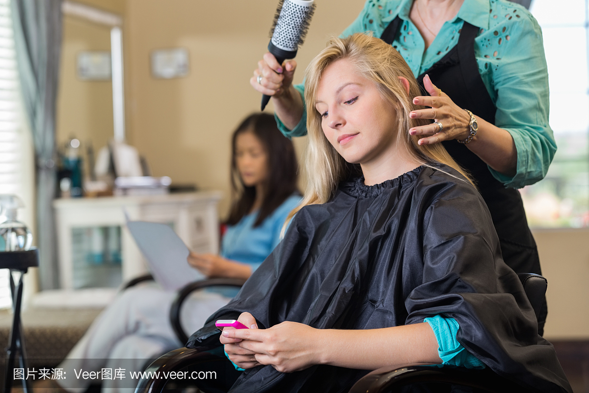 沙龙客户使用智能手机,而造型师剪头发