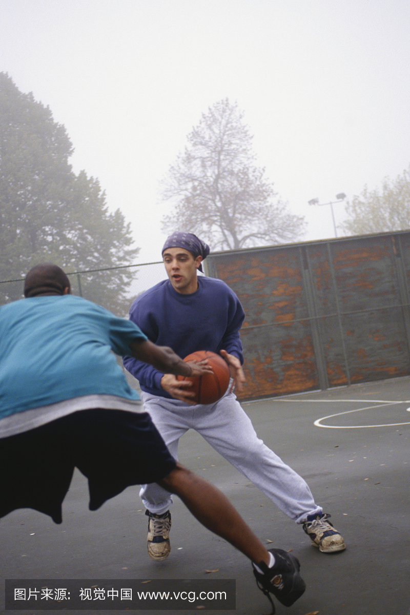 两个年轻人在有雾的公园里打篮球
