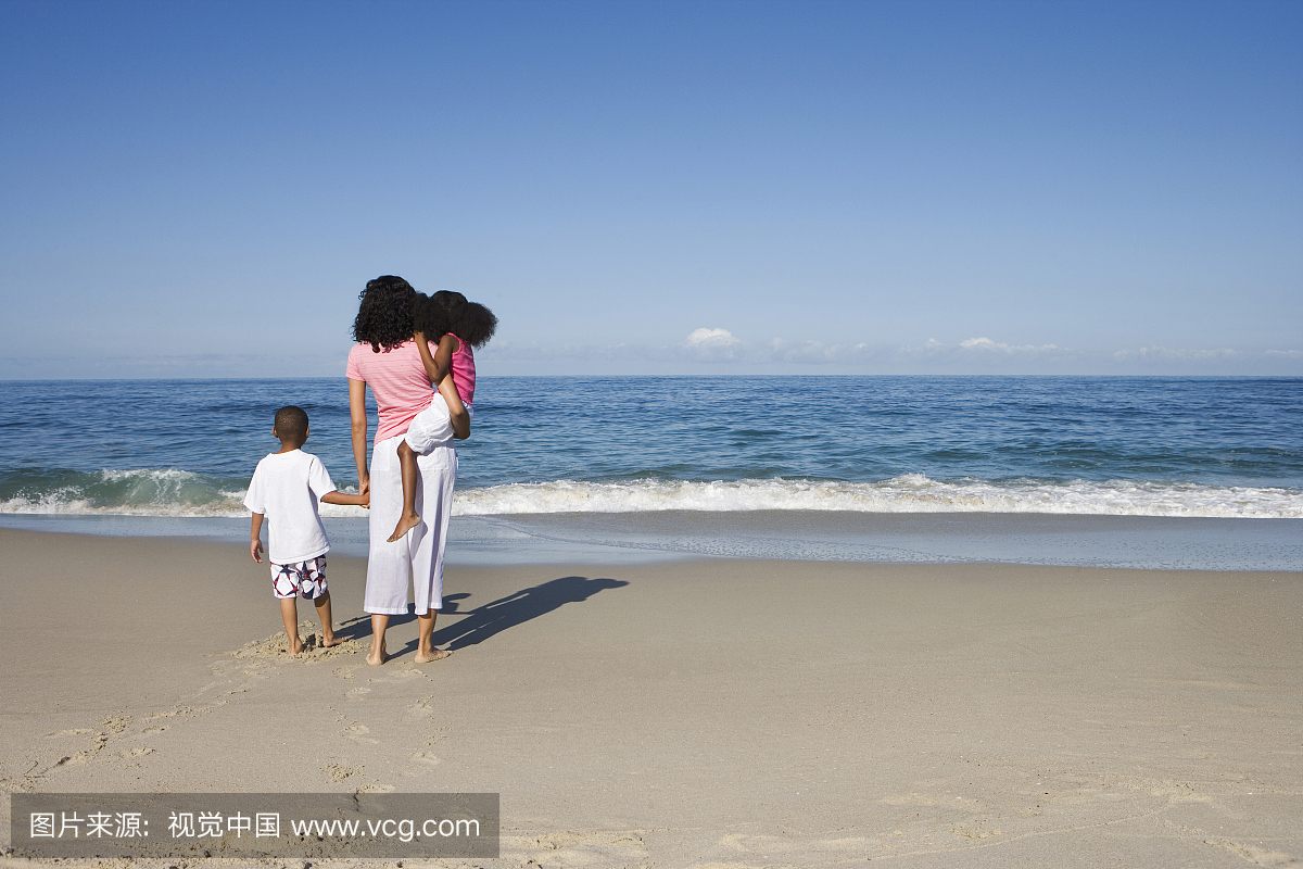 母亲和两个孩子站在沙滩上,看大西洋地平线,后