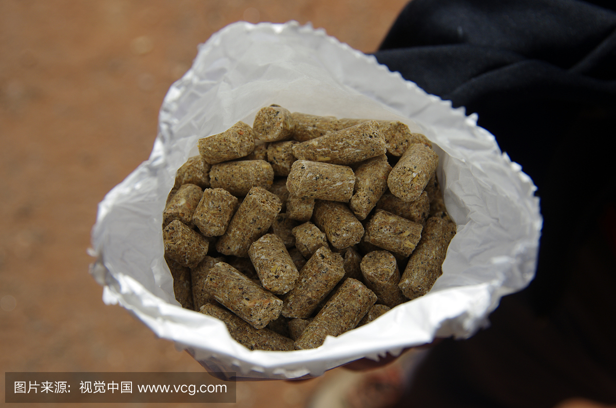 男人在他的手中拿着一个白色的纸袋动物饲料颗