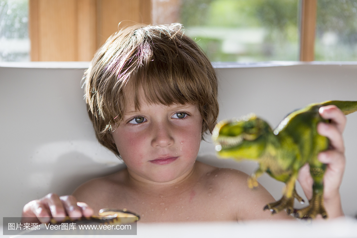 4岁男孩在玩玩具恐龙的浴缸里