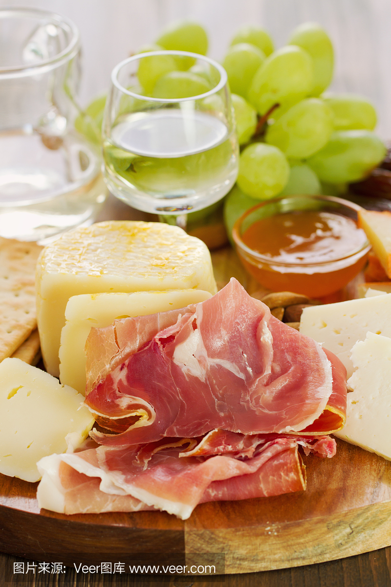 意大利熏火腿芝士和白葡萄酒在棕色背景上的木