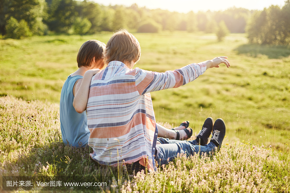 十几岁的男孩用手指向他的女朋友指着远方坐在
