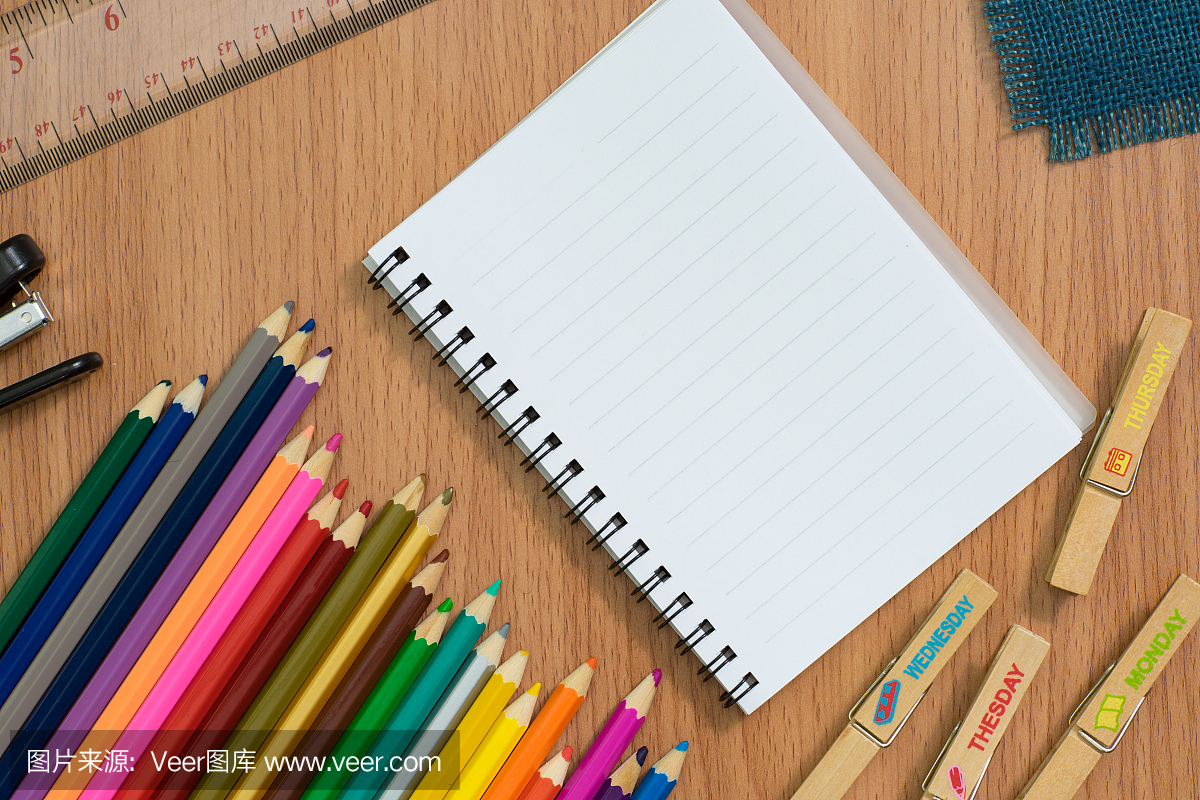 空白的笔记本,五颜六色的pensils和订书机在木