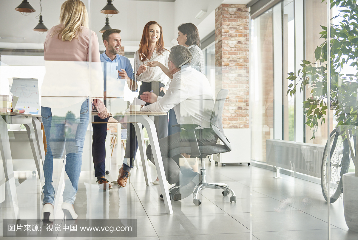 通过站在办公室谈话的同事杯查看