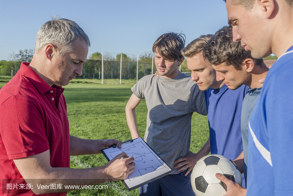 成熟的教练与一群足球运动员交谈的照片