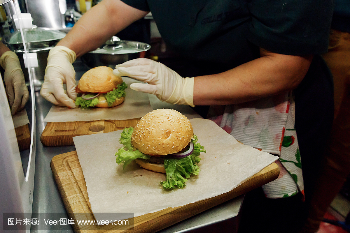 制作汉堡的过程。厨师手在手套烹饪汉堡包和芝