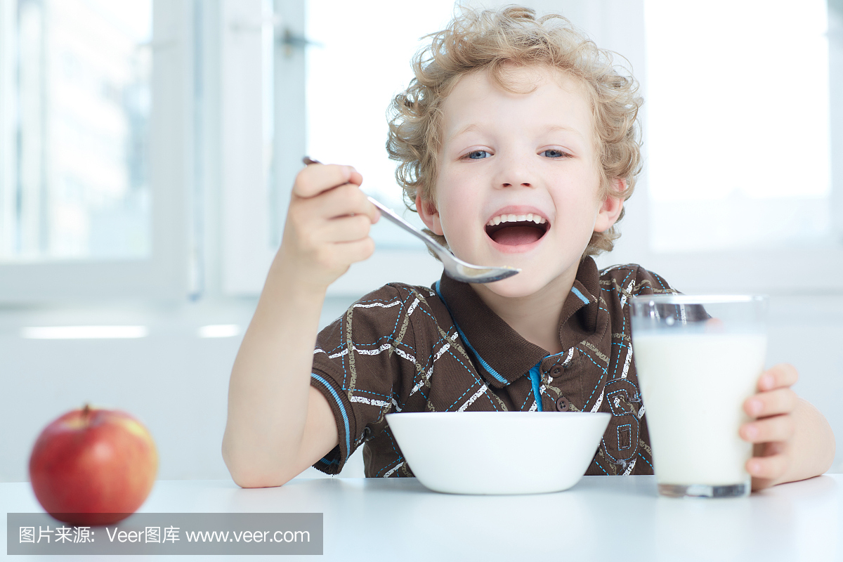 男孩在厨房里吃早餐时吃麦片。