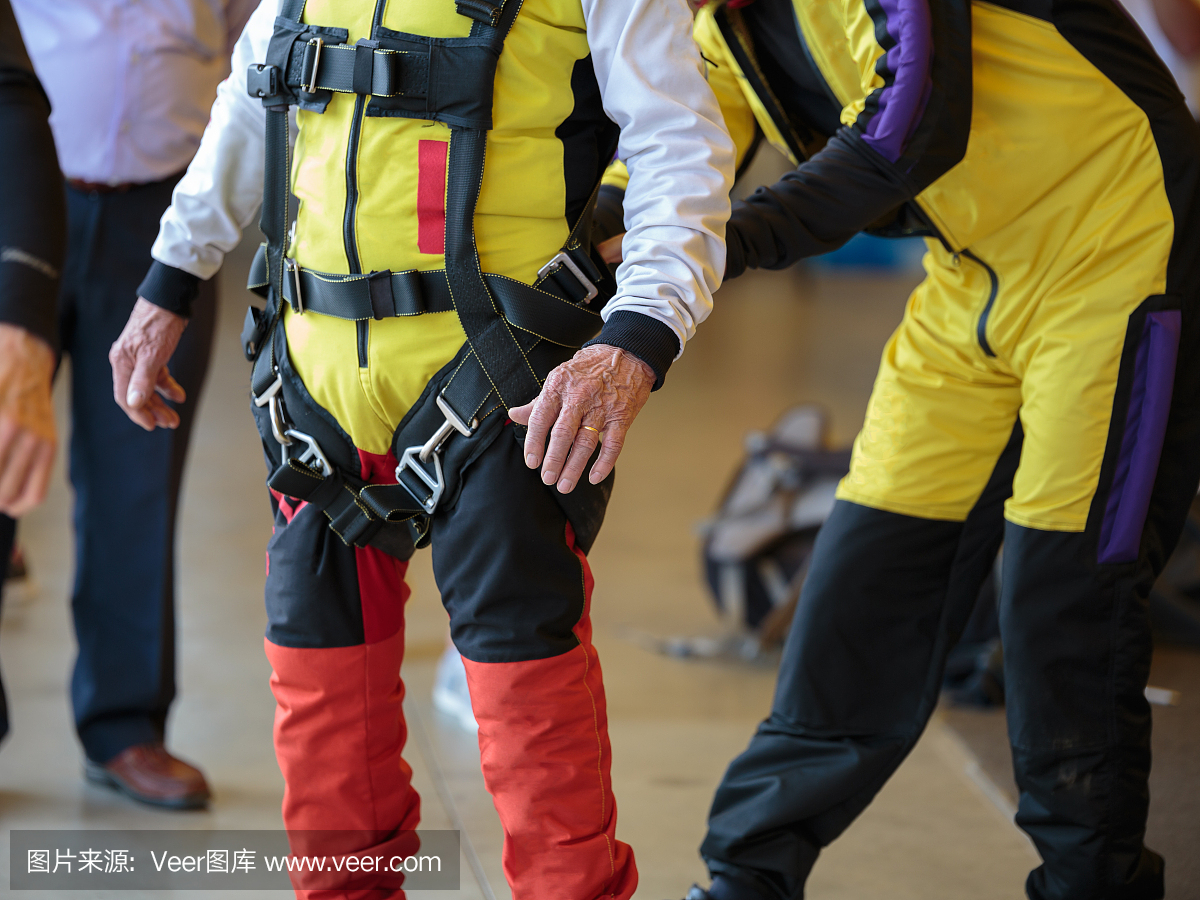 跳伞指导员帮助学徒在他的跳伞运动员西装上系