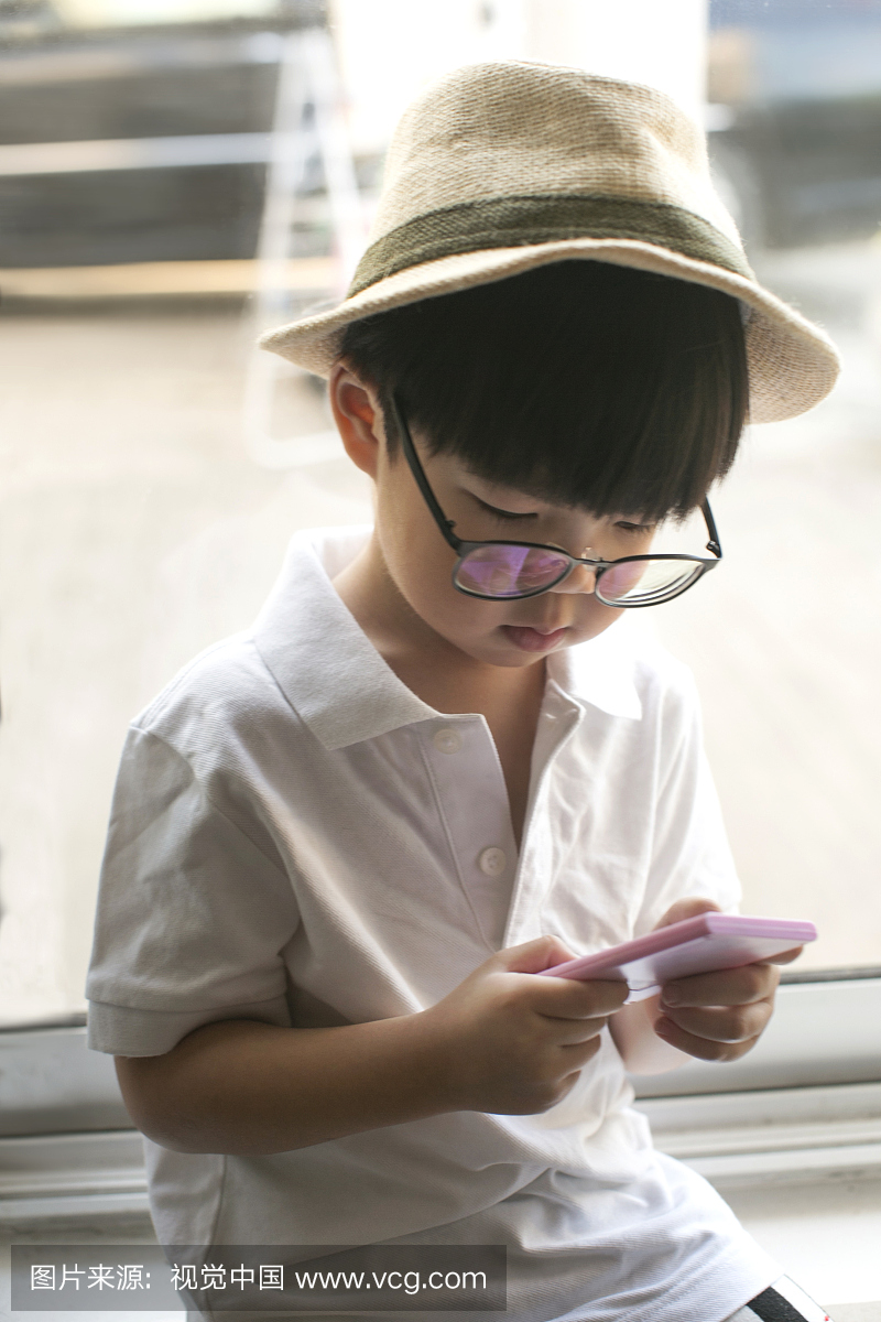 亚洲小男孩专注于手机玩具。