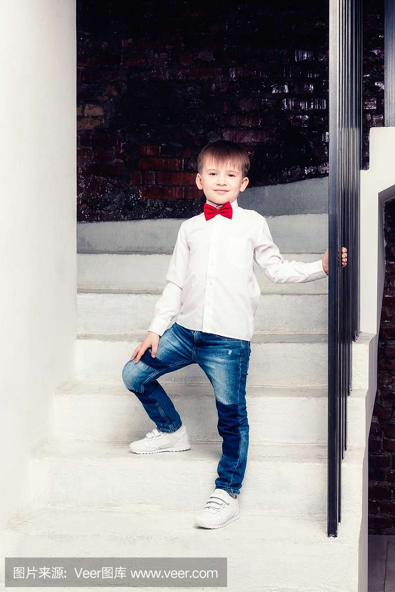 牛仔裤和白衬衫的男孩站在楼梯上