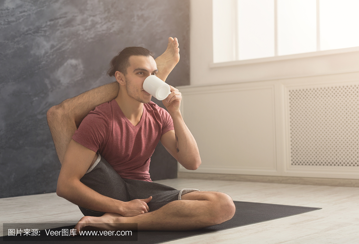 年轻人在灵活的瑜伽姿势喝茶