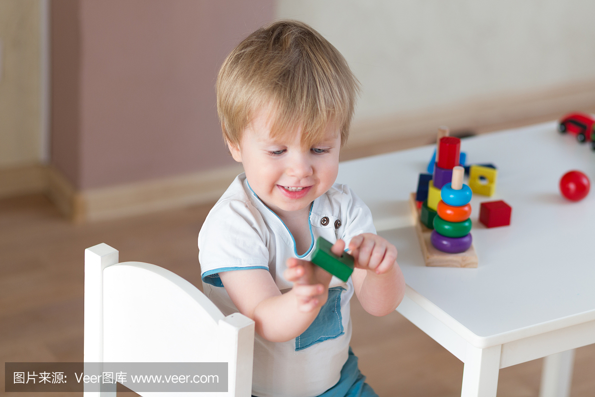 2岁小孩在家玩教育杯玩具。蓝眼睛的小金发宝