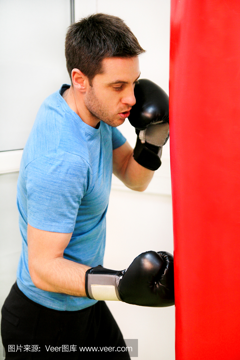 男子拳击手训练是在健身俱乐部用一个冲袋运动