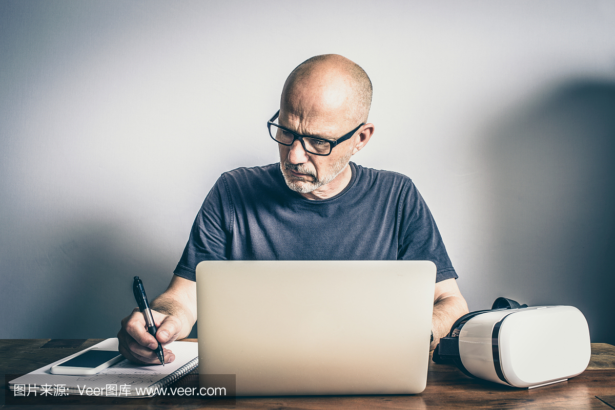 成熟的软件开发人员使用虚拟现实耳机笔记本电