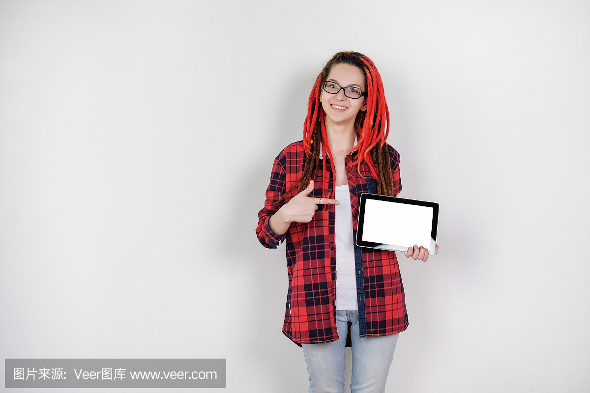 红色辫子的时髦女孩与眼镜持有数字平板电脑的