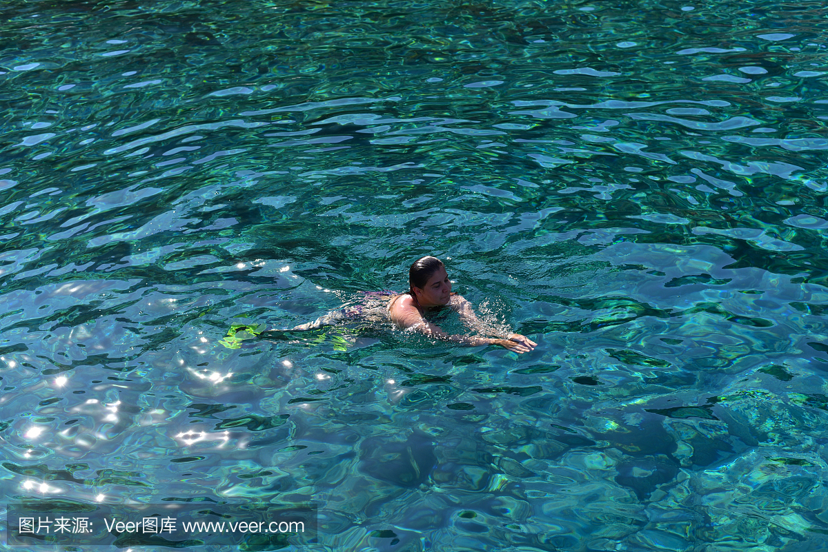 比基尼泳装的年轻女子在透明的浅海浮潜