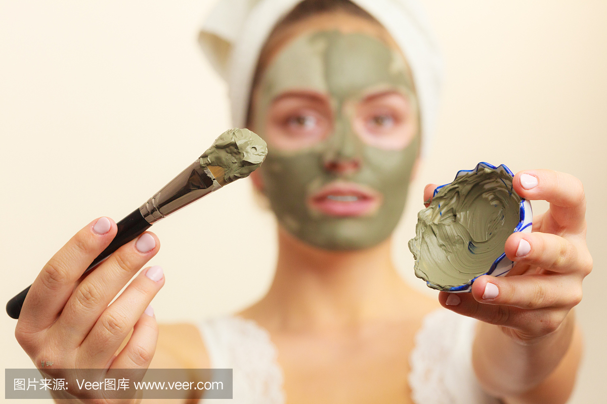 Woman applying with brush clay mud mask to h