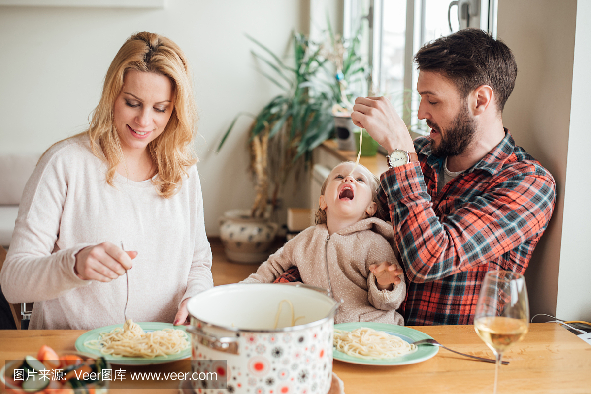 孕妇吃意大利面和她的丈夫喂小孩