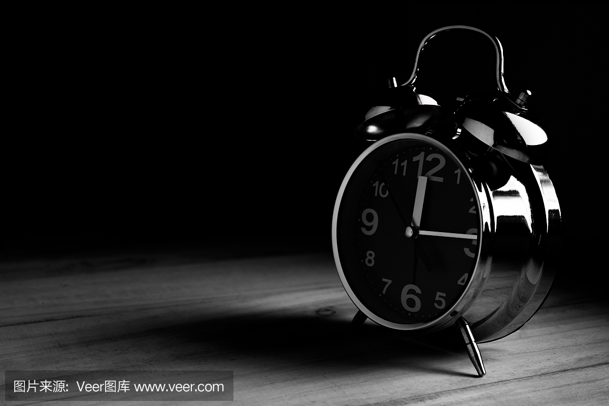时钟在黑色背景,时间概念的黑白色调的木桌上