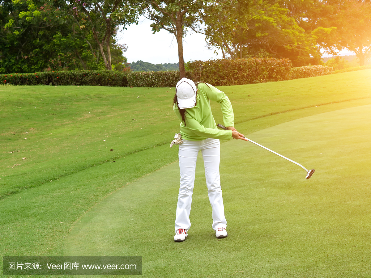 微笑的女子高尔夫球手把球成功的绿色