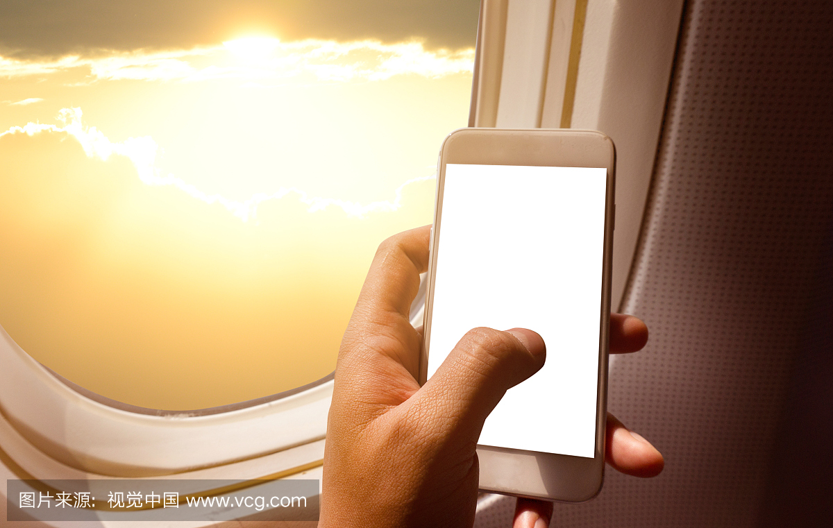 拿着黑屏智能手机的商人手在飞机上靠窗座位和