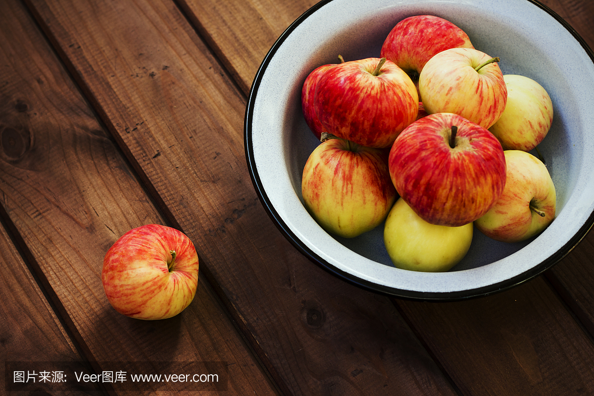 季节性花园红苹果在木制的背景上的金属碗。新